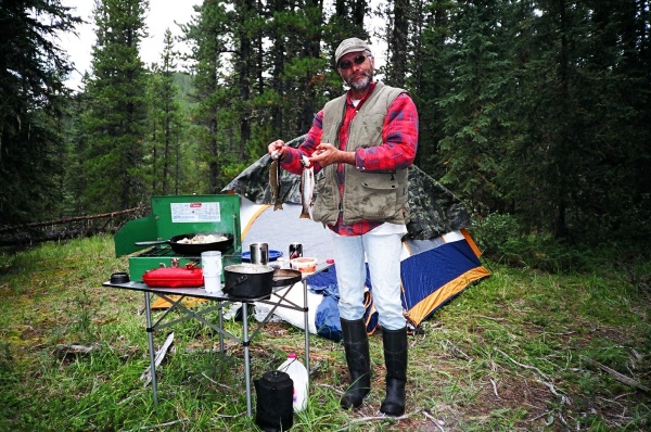 August 20, 2005 - Our camp at Pepper's Lake which is not far off the Forestry Trunk Road south of Nordegg.  Note the rubber boots!  Wayne  (aka Chooch for southerners) stands proudly with the first catch of the day, two very fat brook trout from the chilly waters of Pepper's Lake.